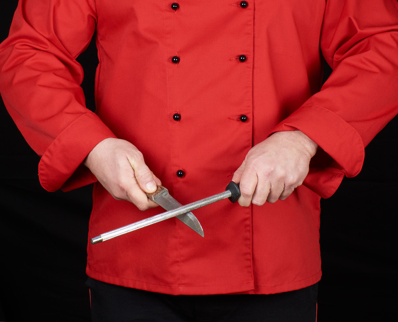 chef in red uniform sharpens a knife