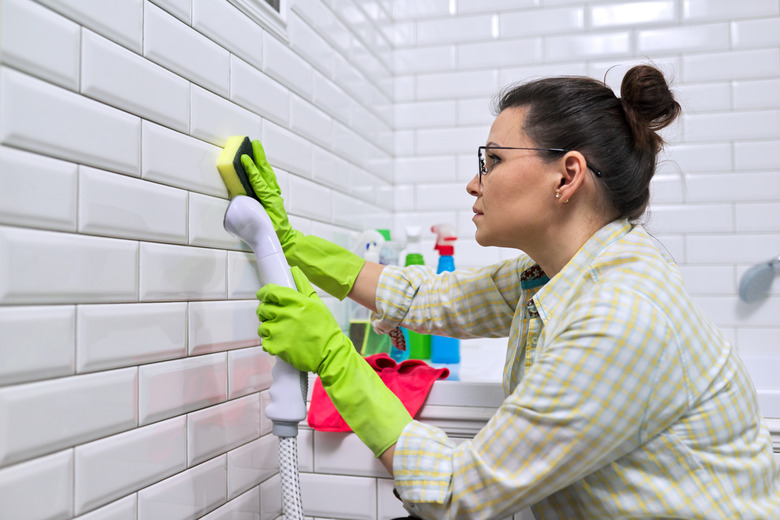 Steam cleaning tile bathroom wall.