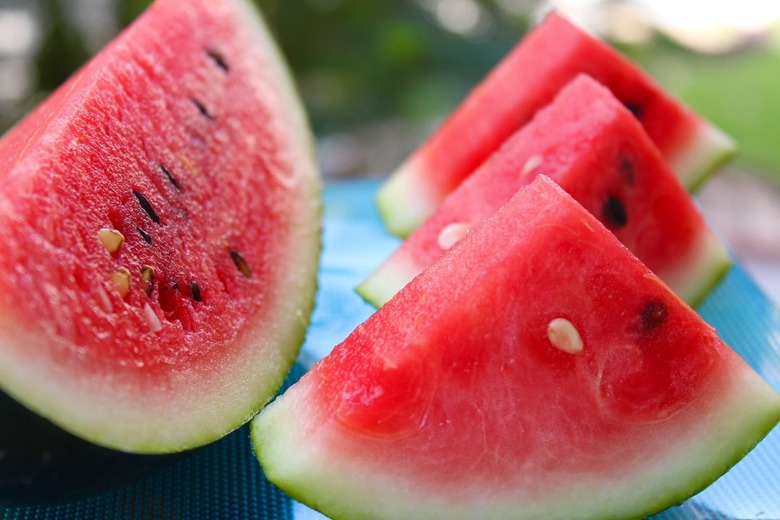 Slices of cut watermelon on a table outside.