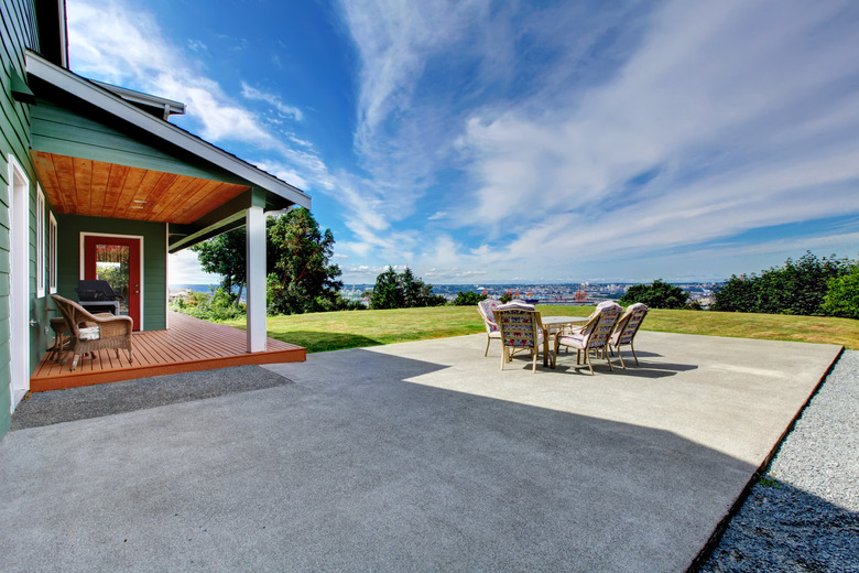 View of large concrete patio area in backyard.