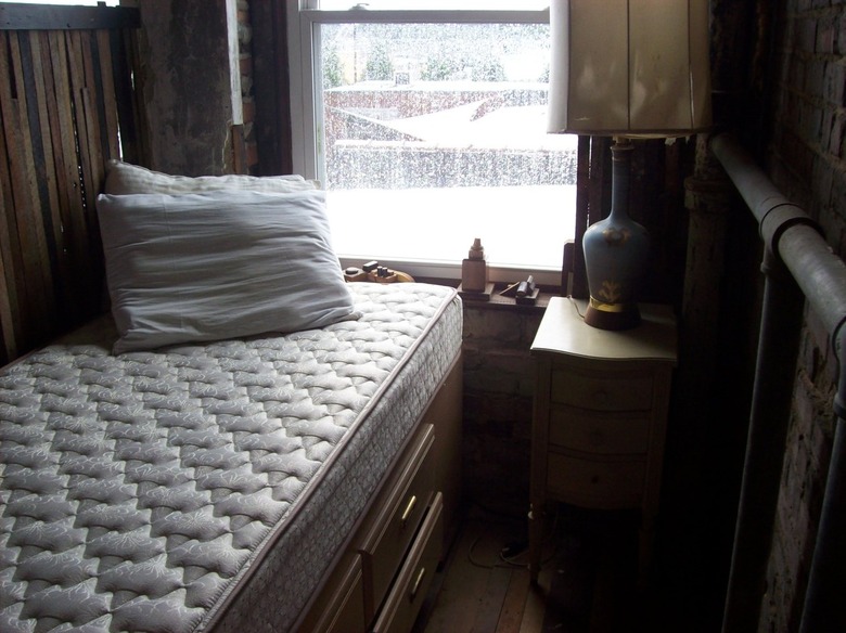 bare mattress with pillows in front of window