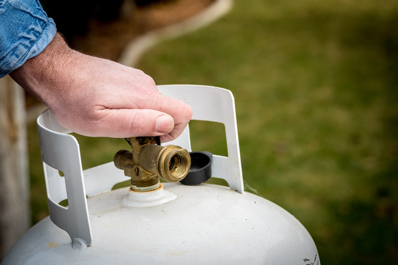 Man turning off a small propane tank.