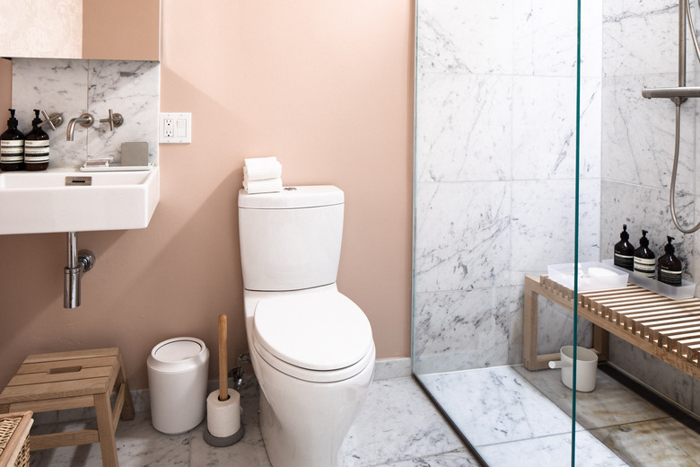 bathroom with marbled tile shower, toilet and wall-mounted sink