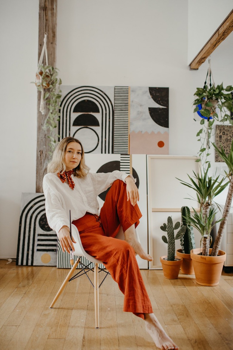 artist Sofia Shu in art studio with paintings leaning up against the wall