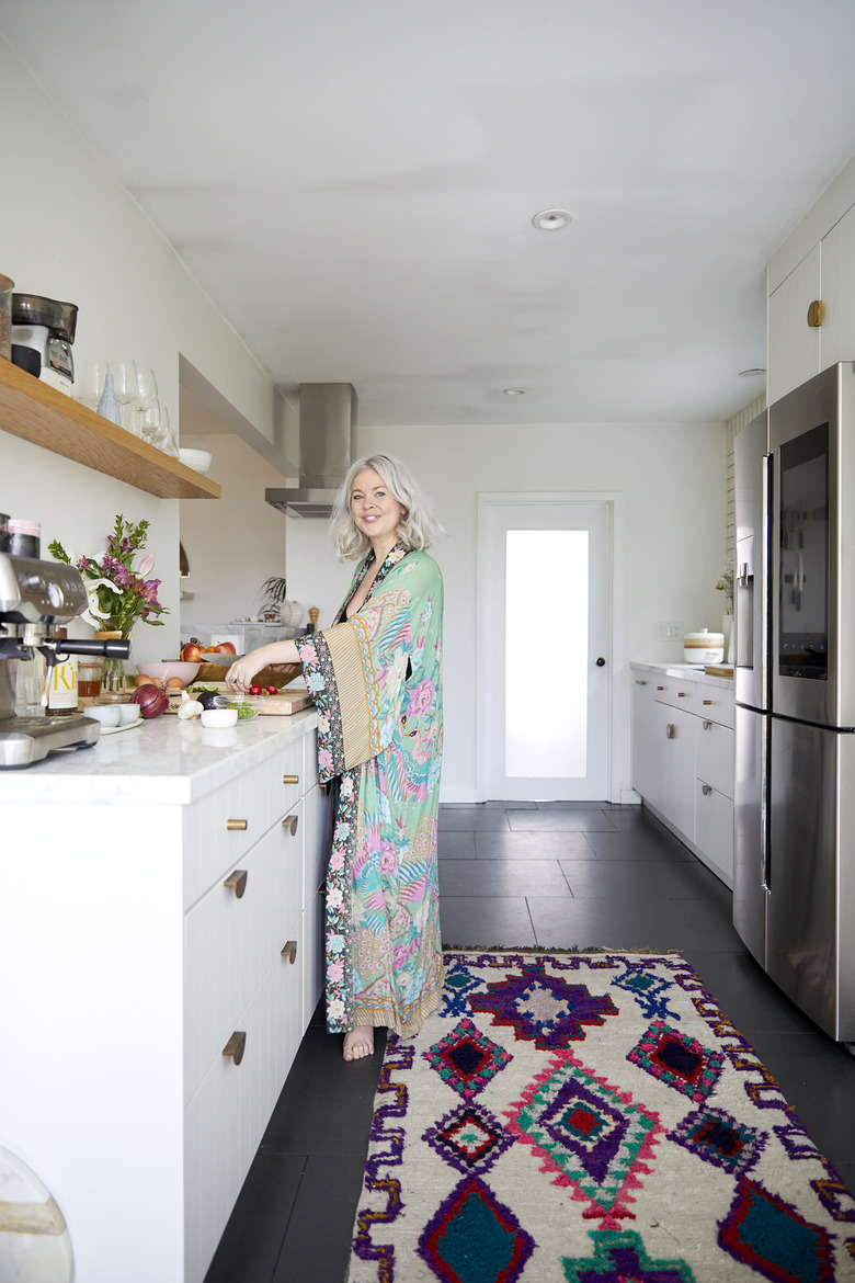 Designlovefest's Bri Emery in kitchen with white cabinets and open shelving