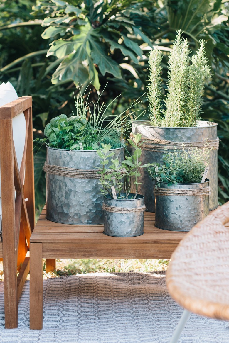 Metal planters with jute twine and plants on an outdoor wood side table