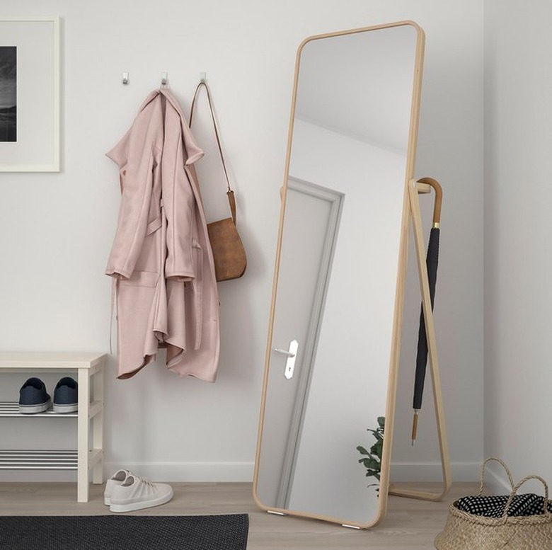 IKEA bedroom idea with a freestanding full-length mirror with a clothing rack on the back. A pink jacket and tan purse hang on wall hooks beside it