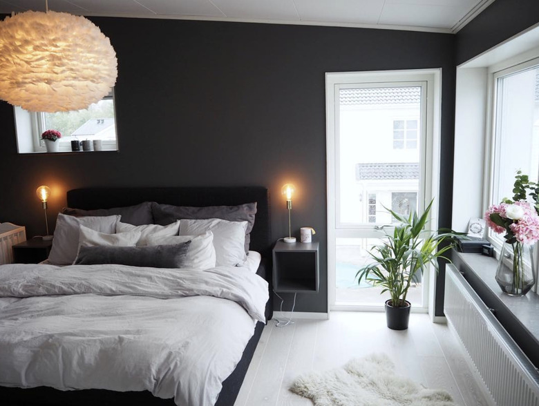 A small gray cubby mounted next to a bed of whites and cool grays, in a dark gray room