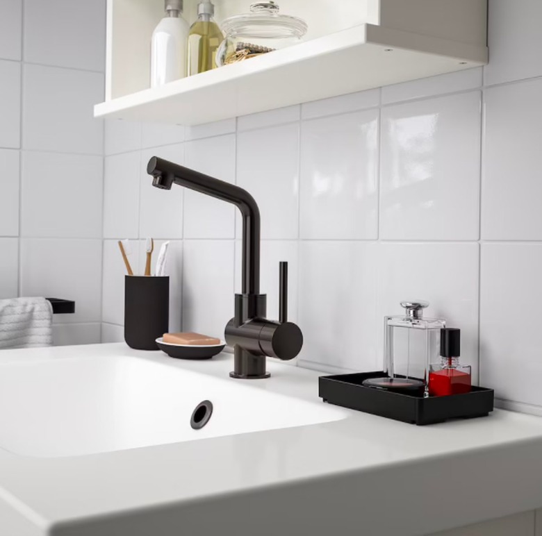 bathroom sink with black faucet and tray