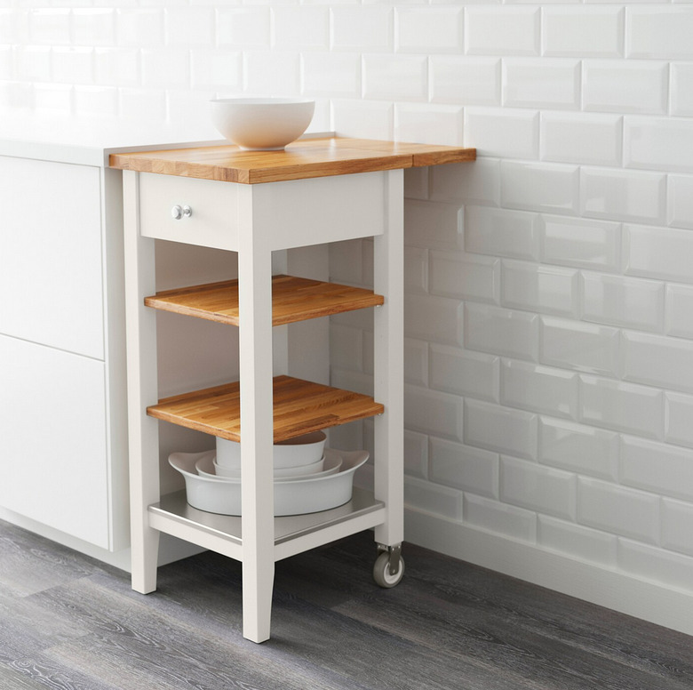 Small IKEA kitchen island with oak and white details against white subway tile backdrop