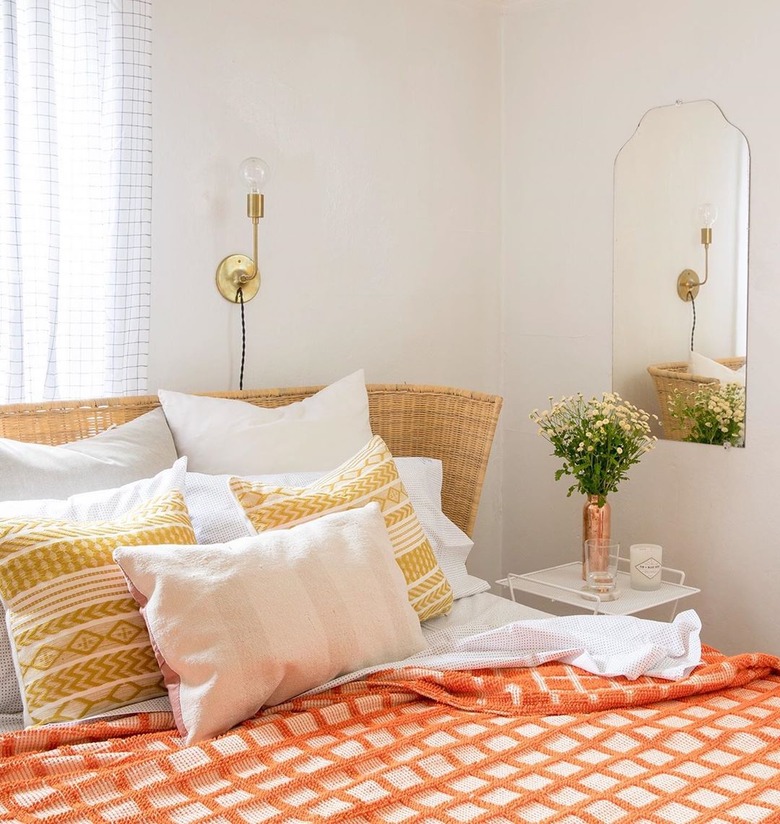 industrial wall sconce with orange and yellow bedroom and cane headboard