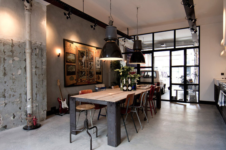 industrial dining room idea with concrete walls and flooring and steel table with wood top and factory style pendant lights