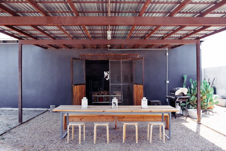 industrial farmhouse table, metal stools, wood bench, metal pergola, gravel.