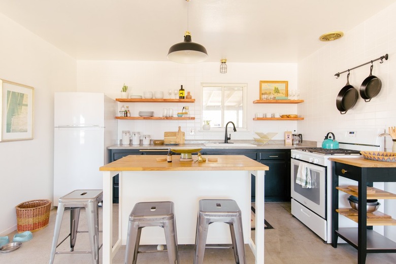 a small island in a large modern kitchen flanked by industrial metal stools