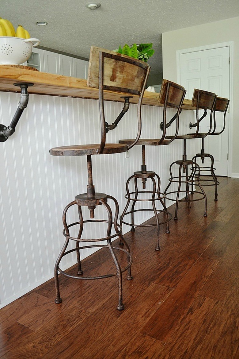 rusted bar stools and white island in industrial kitchen