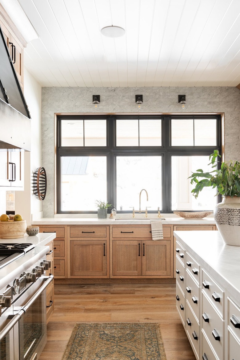 industrial kitchen with black sconces and light wood cabinets