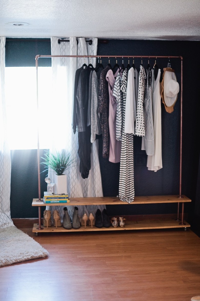 Rolling industrial pipe closet idea in copper with black accent wall