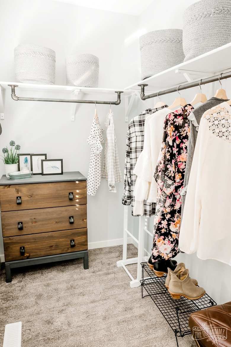 Farmhouse industrial pipe closet idea with white walls and wood dresser