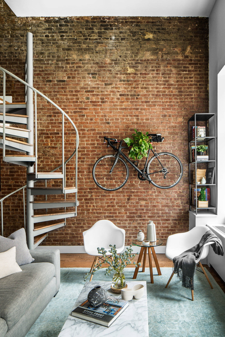 industrial style apartment living room with exposed brick wall and spiral staircase