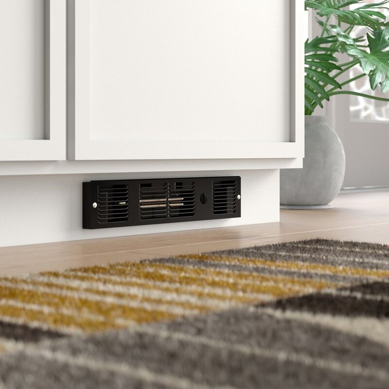 A black electric baseboard on a cabinet's toe kick