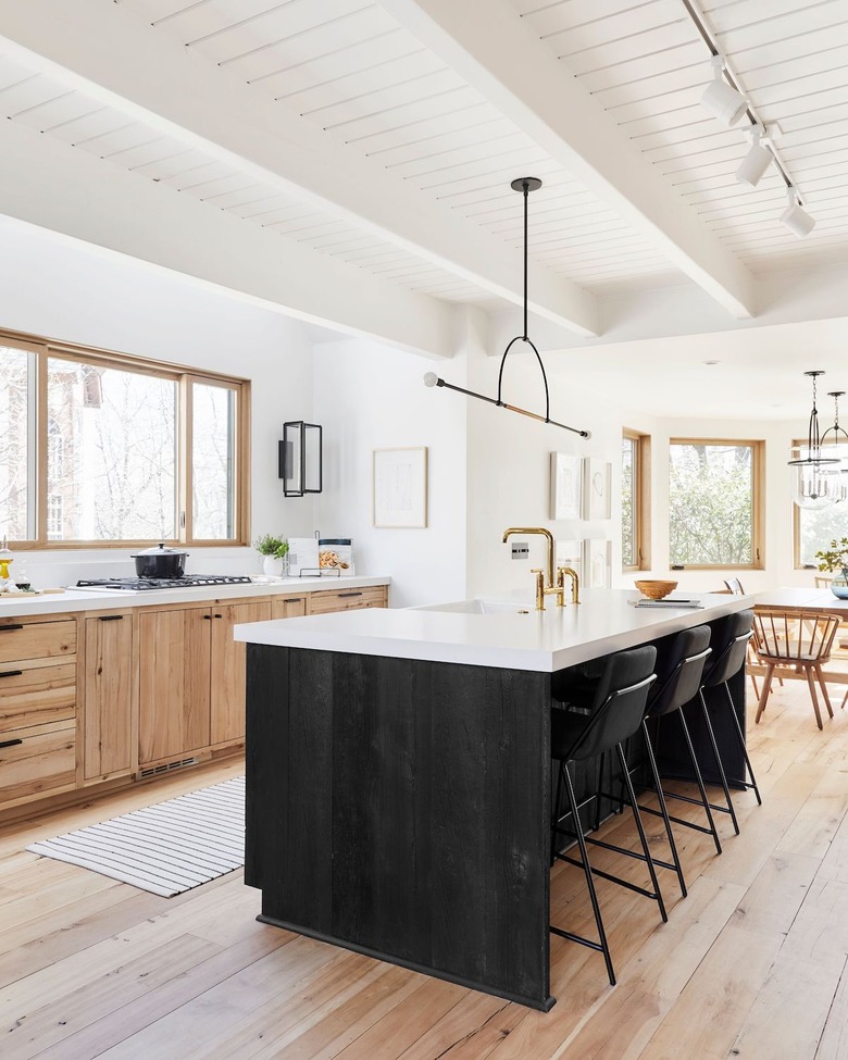 black kitchen cabinet idea for an open and airy white kitchen with mostly raw wood cabinets and a black stained kitchen island