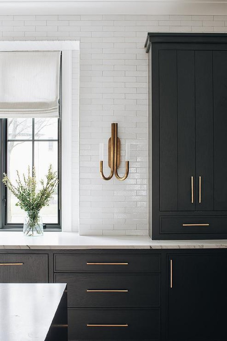 brass wall sconce in traditional kitchen with black kitchen cabinets