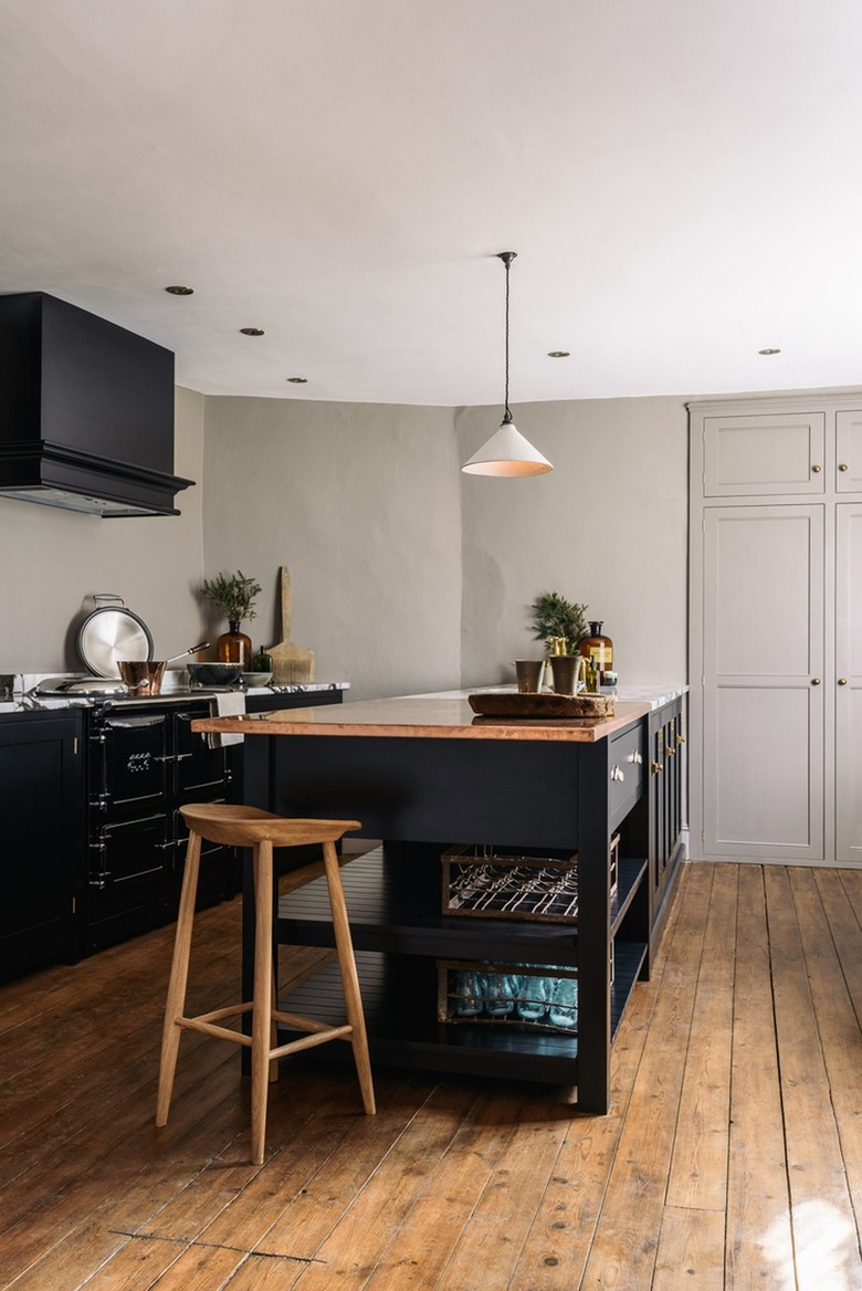 English country kitchen with black cabinets and wood flooring