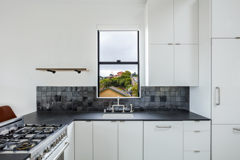 black kitchen backsplash with square glazed tile in white kitchen with black countertops