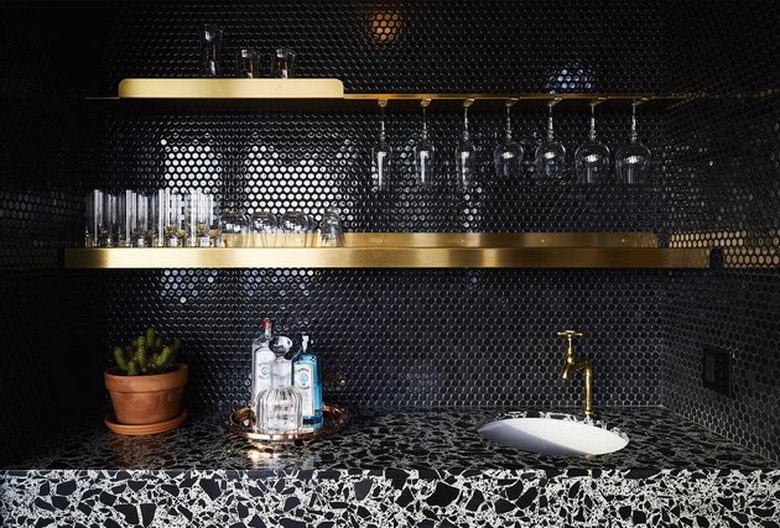 black penny tile mosaic with brass open shelving and terrazzo countertop