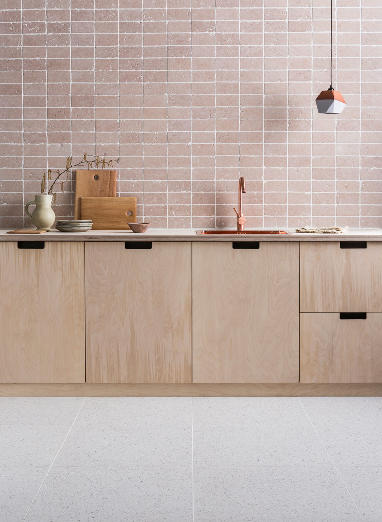 modern kitchen backsplash idea with dusty pink tumbled marble tile paired with plywood cabinets