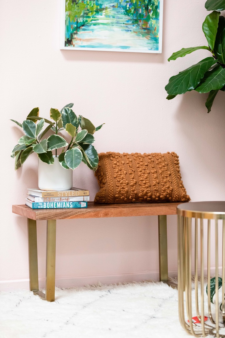 Bench with textured pillow and plant on design books