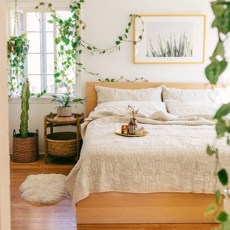 tropical bedroom idea with lush plants and artwork above bed