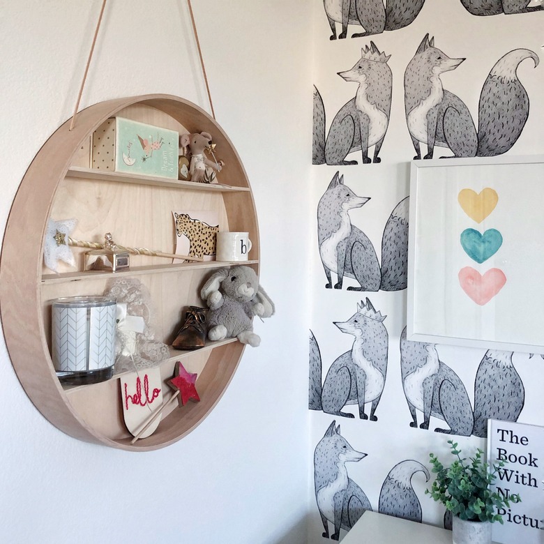 Kids' room organization with circular hanging shelf and black and white fox wallpaper