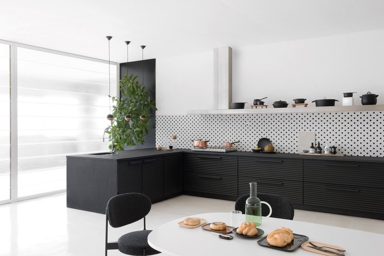 black kitchen accent wall behind tree with black cabinets