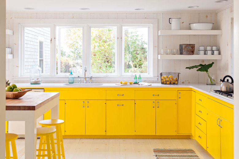 yellow kitchen cabinet color with white walls and countertops and a small island