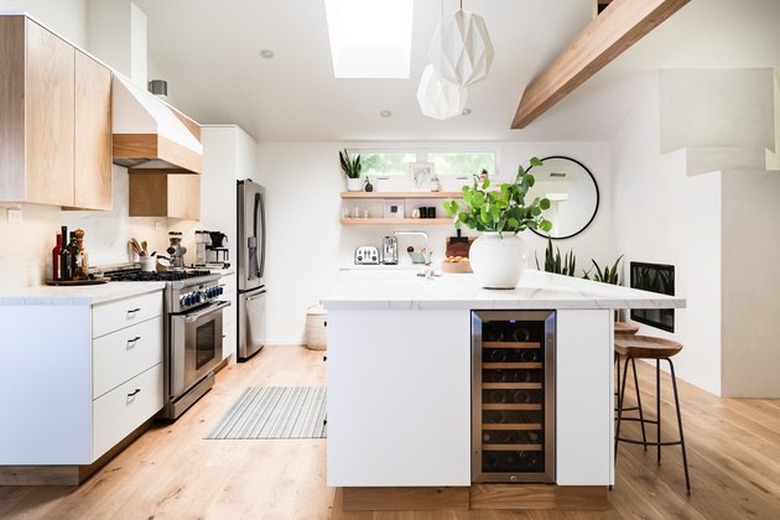 upper wood cabinets and lower white cabinets with large island and wood beam and built-in wine firdge and modern bar stools and skylight