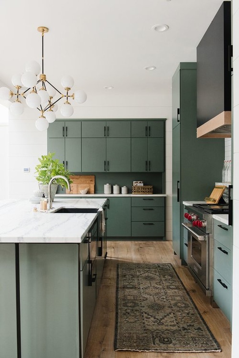 Forest green kitchen colors in kitchen with vintage runner and modern chandelier