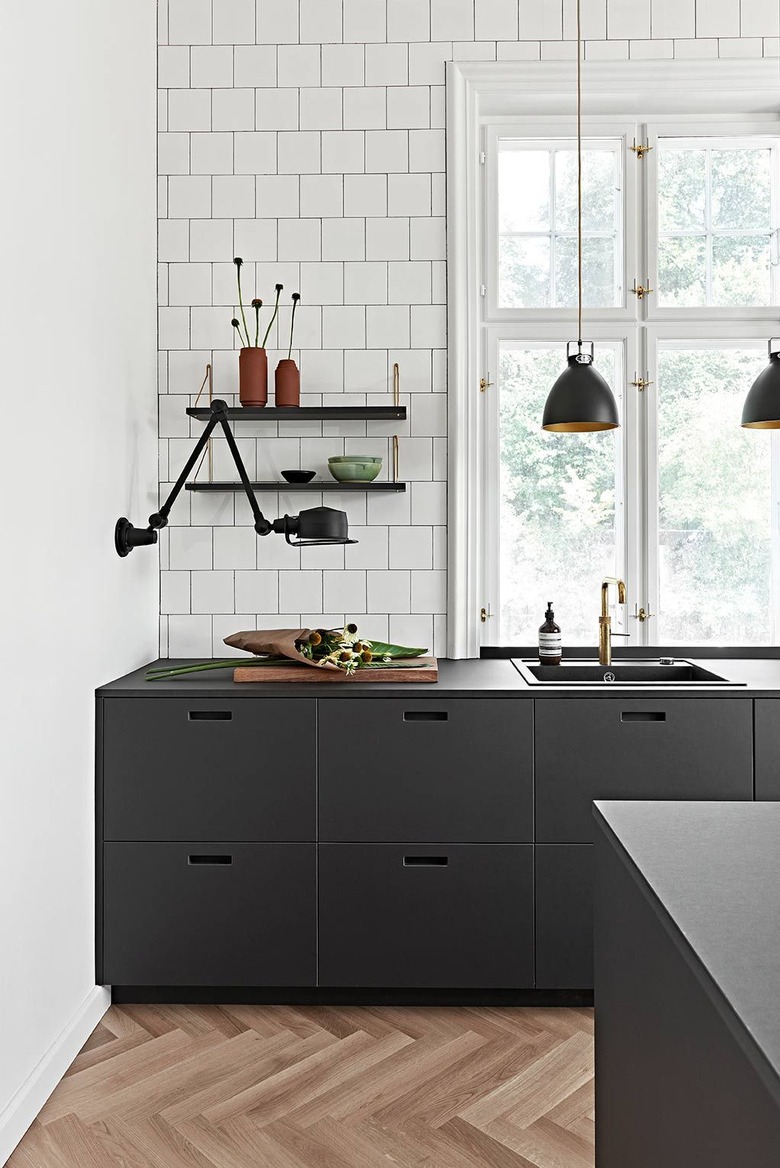 Black and white kitchen colors in kitchen with black lights and herringbone wood floor