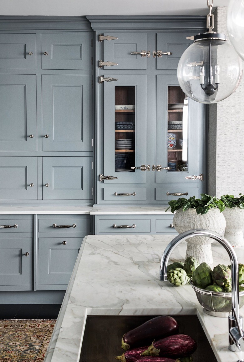 Kitchen with blue gray cabinets, silver hardware and a marble island.