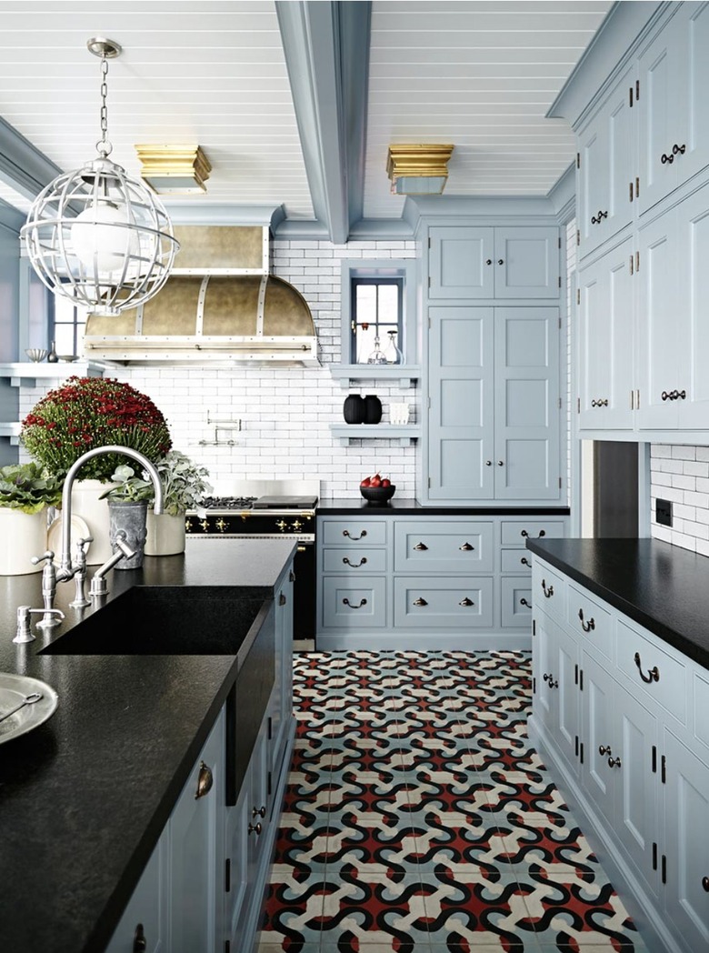 Modern kitchen with blue cabinets, black counter tops and patterned floor tiles.