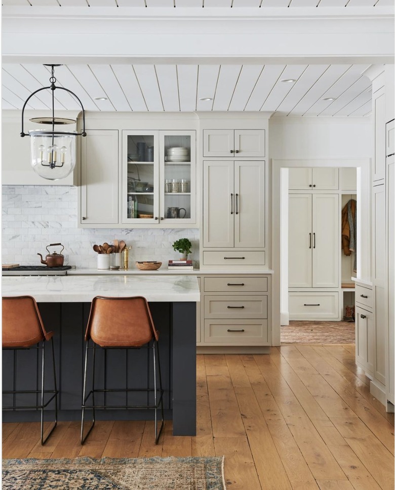 White farmhouse kitchen with countertop cabinets, a grey island and hardwood floors.