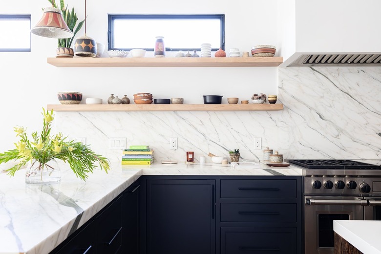 White granite walled kitchen with black cabinets, plants and wood shelves