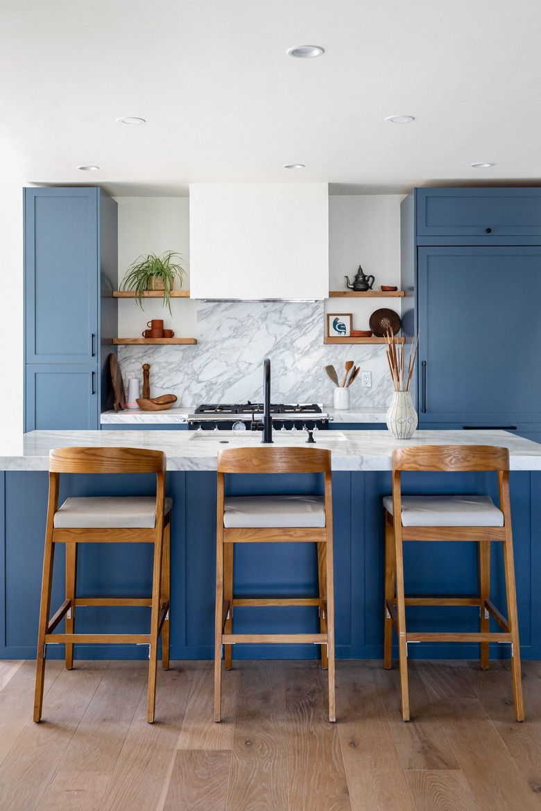 A kitchen with blue cabinets and wood bar stools at a kitchen island