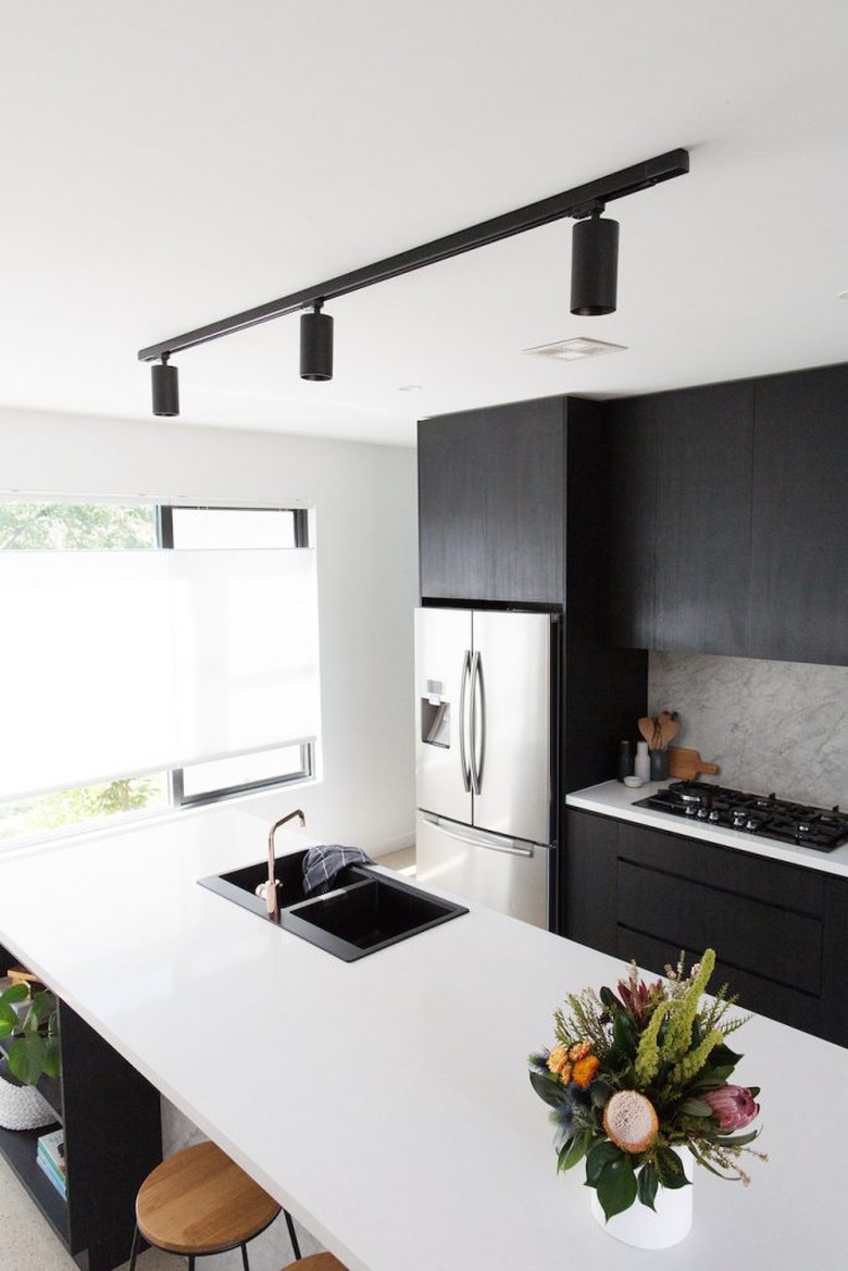 kitchen island sink with black cabinets and white countertops