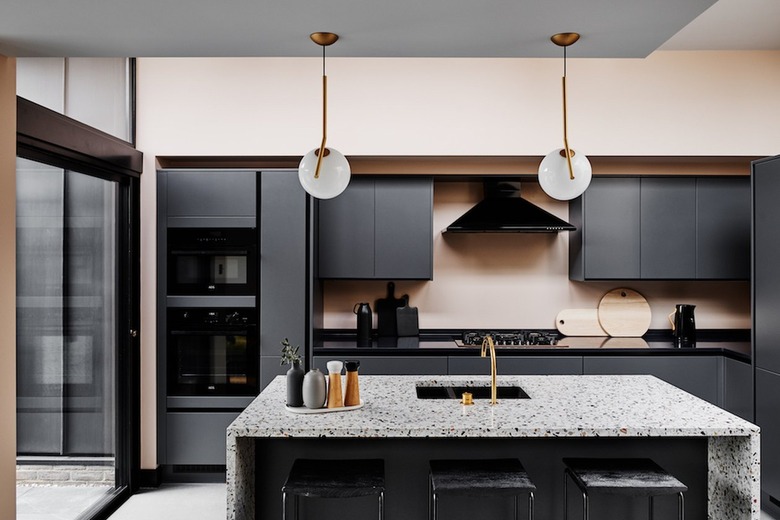 Black cabinets and kitchen island sink with terrazzo countertops