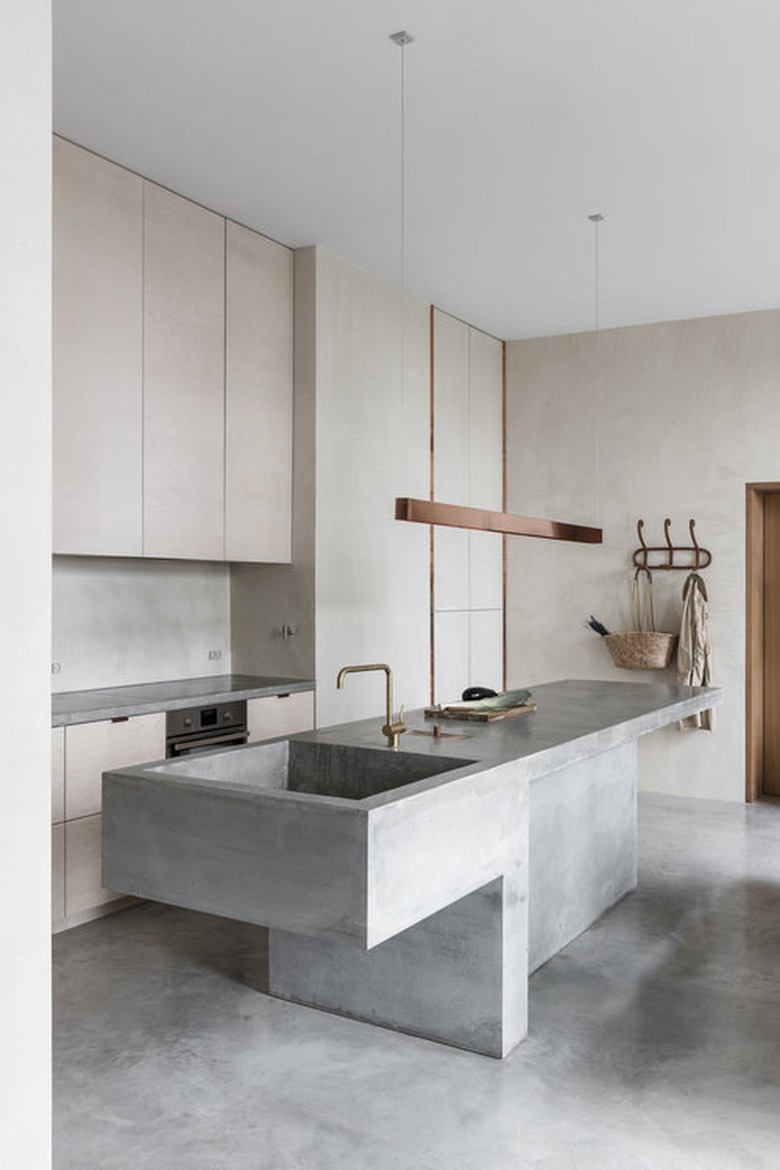 Concrete kitchen island sink with matching concrete floor and modern fixtures