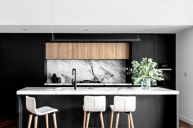 Modern kitchen island sink with black cabinets and marble countertop and backsplash