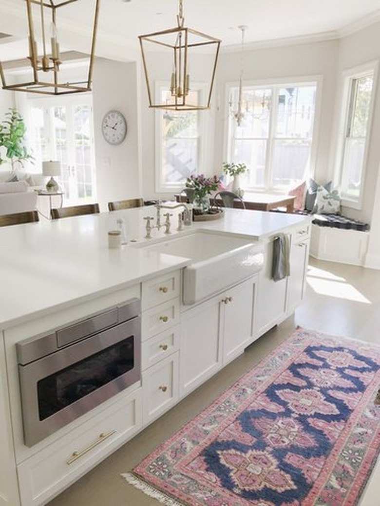 farmhouse kitchen island sink with white cabinets and brass pendant lights