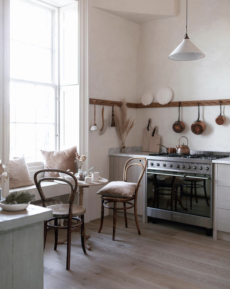 Kitchen nook idea with minimailst kitchen with a professional range, and a tiny bistro table and two vintage bentwood chairs by the window