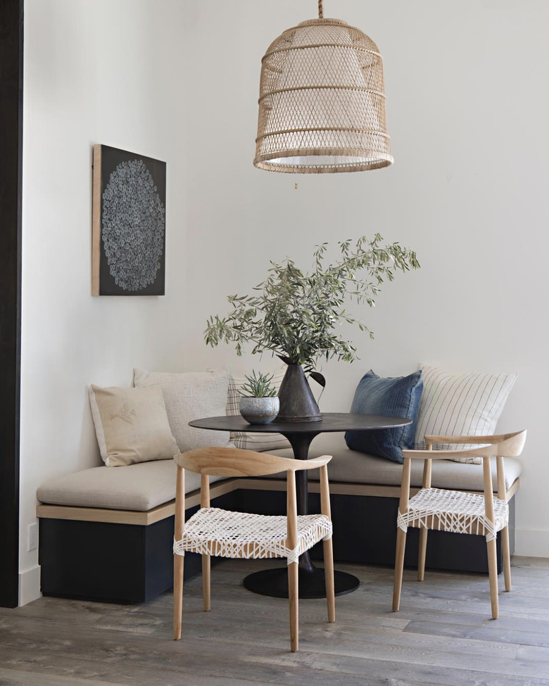 Kitchen nook idea with black tulip table in a corner nook with a neutral banquette and chairs